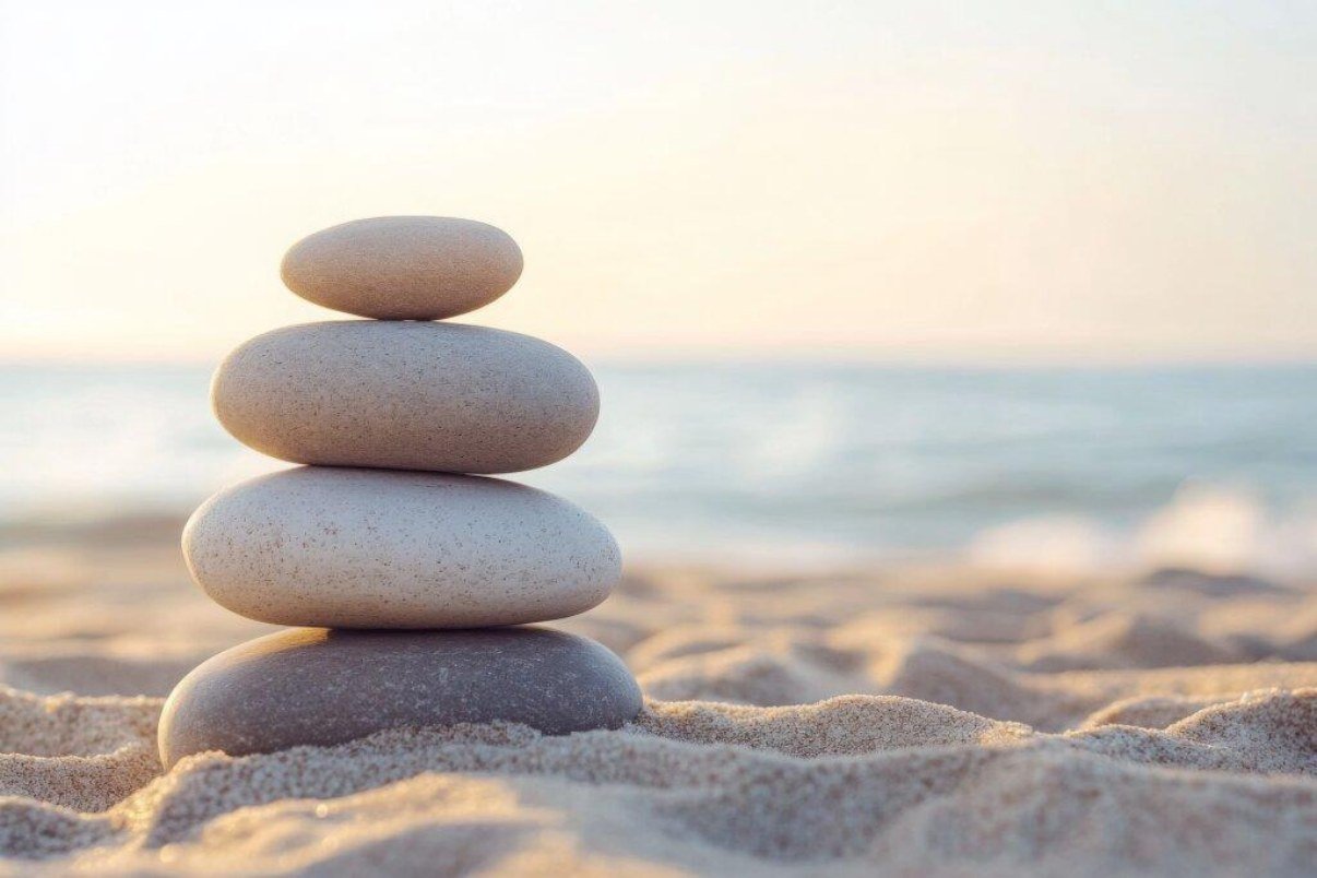Balanced stones stacked on warm sand by the sea